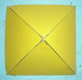 Ein gelbes Quadrat, das durch weiße Kreuzlinien in vier kleinere Dreiecke geteilt ist, symbolisch ähnlich den vier Himmelsrichtungen auf einer Karte.