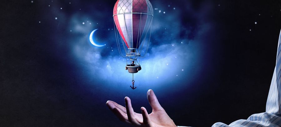 Ein fantasievolles Bild eines Hei&szlig;luftballons, der &uuml;ber einer Hand schwebt, mit einem dunklen, stern&uuml;bers&auml;ten Himmel und einem sichelf&ouml;rmigen Mond im Hintergrund.