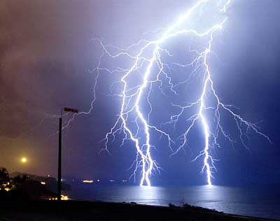 Nachtlandschaft mit hellen Blitzen, die ins Meer einschlagen, unter atmosph&auml;rischen Bedingungen, die von der Sch&ouml;pfung des Himmels widergespiegelt werden.