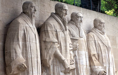 Skulptur von vier m&auml;nnlichen Figuren in Roben, die in Stein gemei&szlig;elt sind und in eine Reihe an einer Wand stehen.