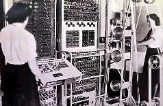 Historisches Schwarz-Wei&szlig;-Foto von zwei Frauen, die an einem gro&szlig;en, komplexen Computer der 1940er Jahre arbeiten, mit zahlreichen Schaltern und Kabeln.