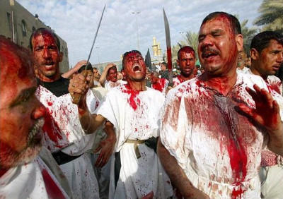 Gruppe von M&auml;nnern in wei&szlig;en Gew&auml;ndern bedeckt mit roter Farbe, die Schwerter schwingen und starke Emotionen w&auml;hrend einer zeremoniellen Versammlung ausdr&uuml;cken.