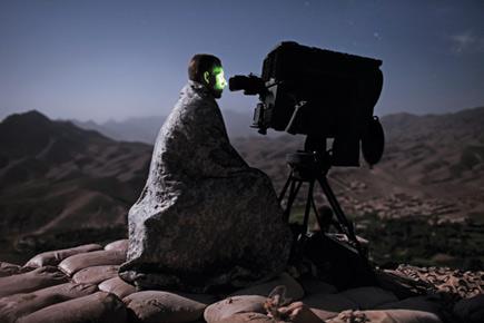 Ein Astronom beobachtet die Mazzaroth mittels eines Teleskops auf einem stein&uuml;bers&auml;ten H&uuml;gel bei Nacht. Sein Gesicht ist durch die gr&uuml;ne Beleuchtung des Teleskopokulars erhellt und die entfernten Berge zeichnen sich im schwachen Mondlicht ab.