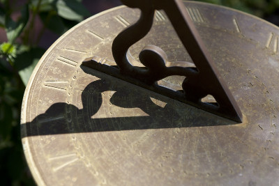 Nahaufnahme einer Sonnenuhr aus Messing, auf der der Schatten eines dreidimensionalen metallenen Gnomons f&auml;llt, der einem Tier nachempfunden ist, welches symbolisch mit dem Mazzaroth in Verbindung steht.