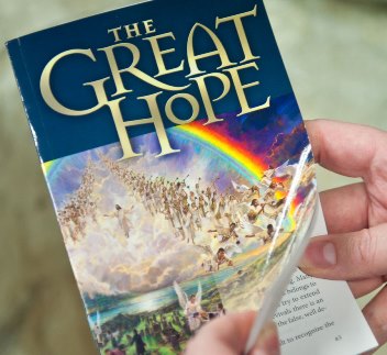 Eine Hand h&auml;lt ein Buch mit dem Titel "The Great Hope", auf dessen Cover ein gemaltes Bild einer Menschenmenge unter einem bunten Regenbogen abgebildet ist.
