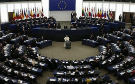 Blick in den halbrunden Plenarsaal des Europ&auml;ischen Parlaments w&auml;hrend einer Sitzung mit vielen Abgeordneten und Flaggen der Mitgliedsl&auml;nder im Hintergrund.