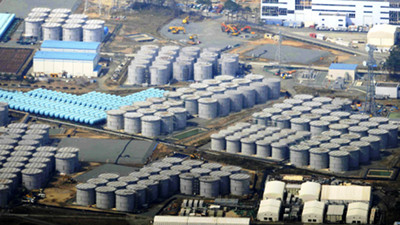 Luftaufnahme eines gro&szlig;en Industriegel&auml;ndes mit zahlreichen wei&szlig;en zylindrischen Tanks, die systematisch angeordnet sind. Hintergrund zeigt weitere industrielle Bauten und Baufahrzeuge.