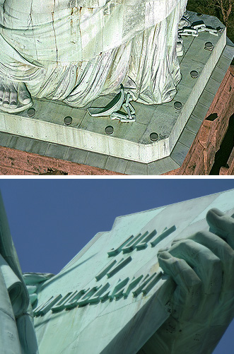 Detaillierte Nahaufnahme der gravierten Tafel, die die Figur der Freiheitsstatue in ihren H&auml;nden h&auml;lt, unterhalb ein Blick auf die drapierte Robe und die Basis der Statue.