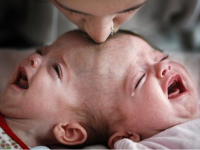 Ein Baby weint heftig, w&auml;hrend eine Erwachsene liebevoll ihre Nase an die Stirn des Babys dr&uuml;ckt.