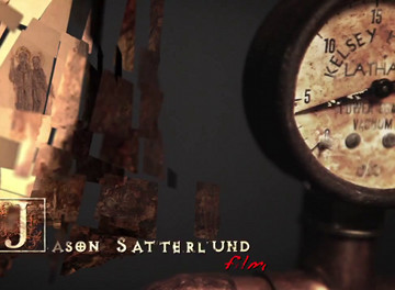 Ein Nahaufnahmebild zeigt ein altes Teleskop, das auf eine Wand mit verschwommenen Bildern und Text gerichtet ist, darunter der Name "Jason Satterlund" in roter Schrift.
