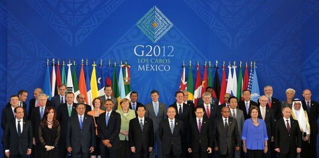 Gruppenfoto von weltweiten Staats- und Regierungschefs vor einer Reihe internationaler Flaggen bei einem G20-Gipfel in Los Cabos, Mexiko, 2012. Ein Banner mit der Aufschrift "G2012 Los Cabos Mexico" ist oben im Bild zentriert.