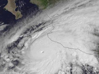 Satellitenbild eines gro&szlig;en tropischen Wirbelsturms nahe einer K&uuml;stenlinie. Die Bildung zeigt ein ausgepr&auml;gtes Auge, umgeben von dichten Wolkenfeldern.