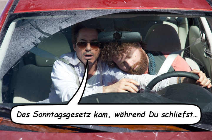 Zwei Männer in einem Auto; der eine, mit dunklen Haaren und Sonnenbrille, blickt ernsthaft auf die Straße, während der andere, mit rotem Bart, erschöpft auf dem Lenkrad schläft. Eine Sprechblase sagt: "Das Sonntagsgesetz kam, während Du schliefst..."