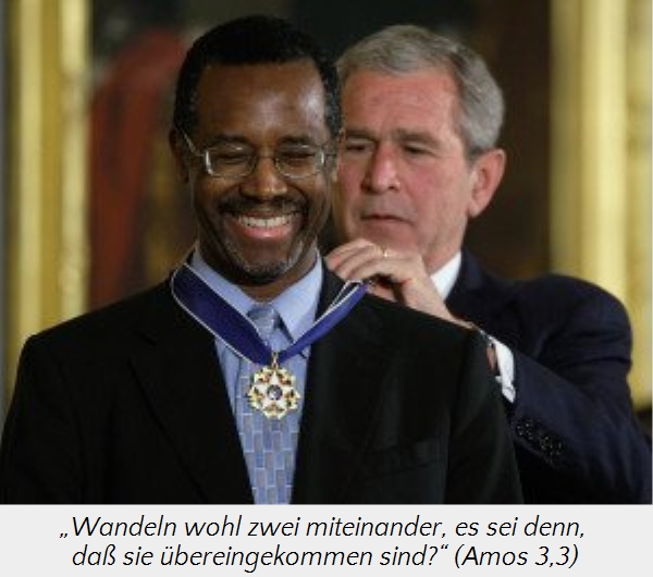 Ein &auml;lterer wei&szlig;er Mann legt einem lachenden schwarzen Mann, der eine Medaille tr&auml;gt, freundlich die Hand auf die Schulter in einem eleganten Raum.